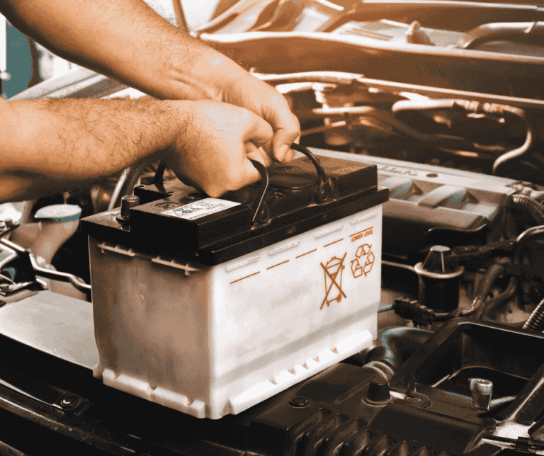 Technician handling car battery for electrical repair in Lahore – IQ Wheels Hybrids Auto Zone
